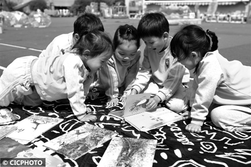 4月22日,在青岛市市北区海安幼儿园开展的“阅读节”读书活动上,小朋友们在阅读动物主题绘本 新华社发